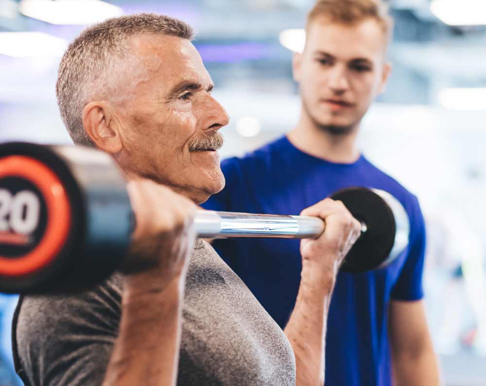 Man lifting weights with trainer