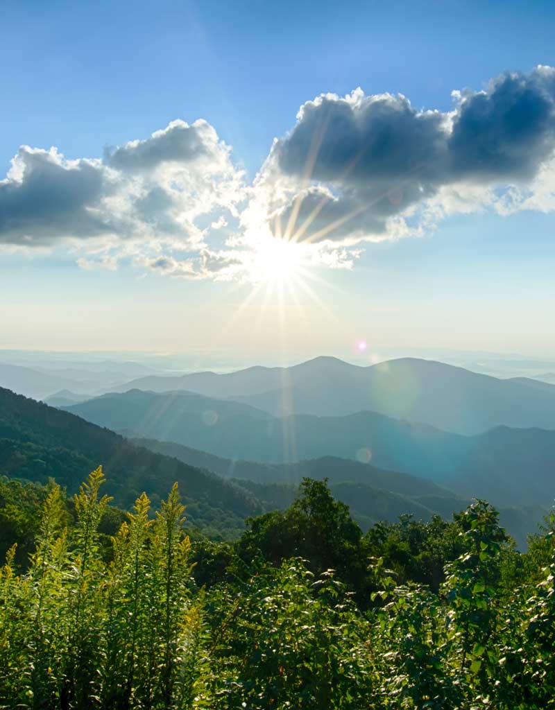 sunburst over mountains in summer